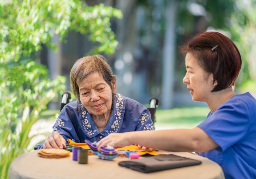 Elderly,Woman,With,Caregiver,In,The,Needle,Crafts,Occupational,Therapy